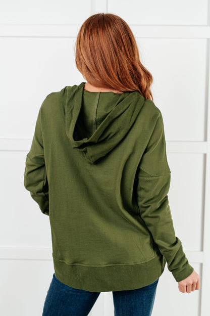 Person wearing an olive green hoodie with a white background