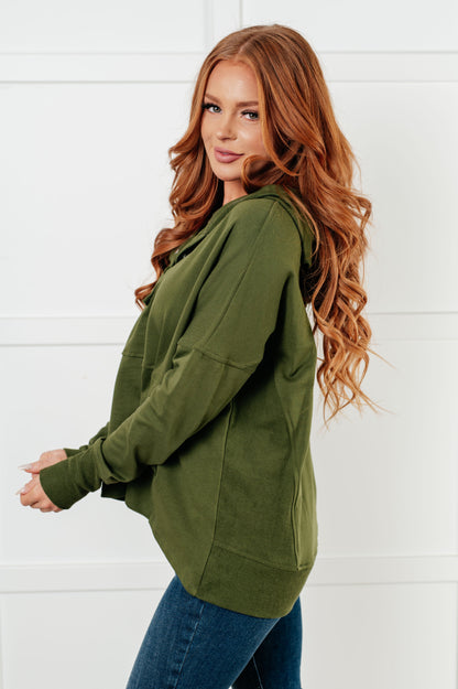 Woman wearing an olive green hoodie against a white background