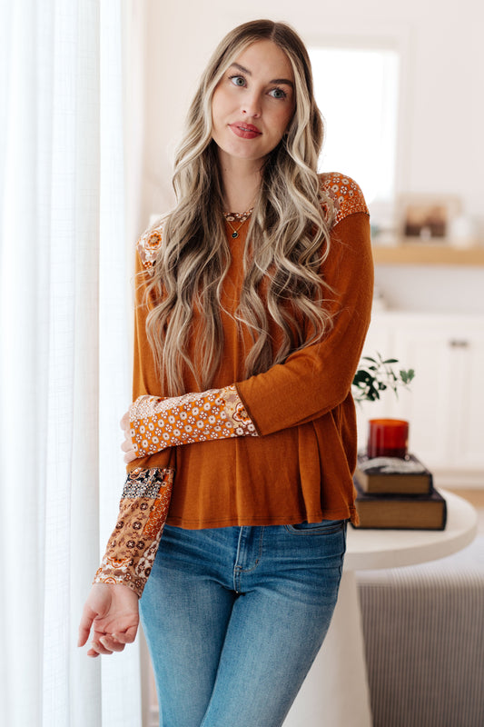 Woman wearing a patterned blouse and jeans in a living room setting