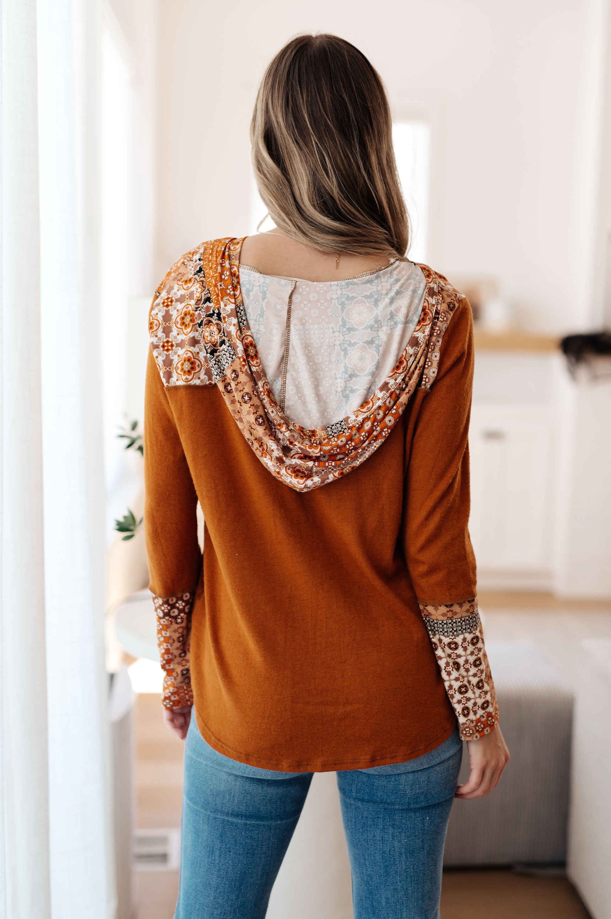 Person wearing a brown top with floral patterns in a room.