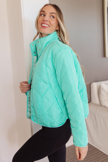Woman wearing a teal quilted jacket in an indoor setting