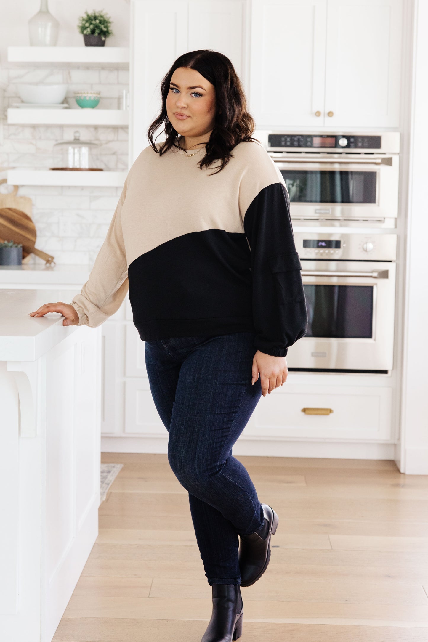 Woman wearing a beige and black sweater in a kitchen