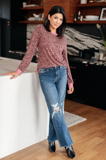Woman in a kitchen wearing a patterned top and jeans.