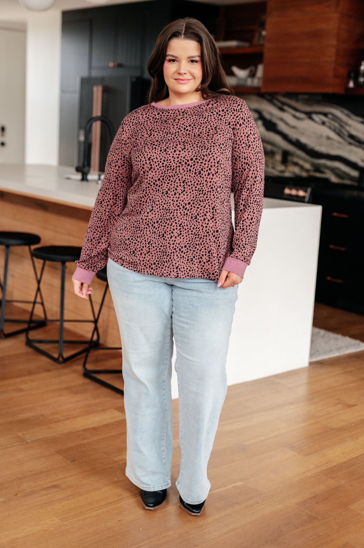 Woman wearing a patterned sweater and light jeans in a kitchen setting