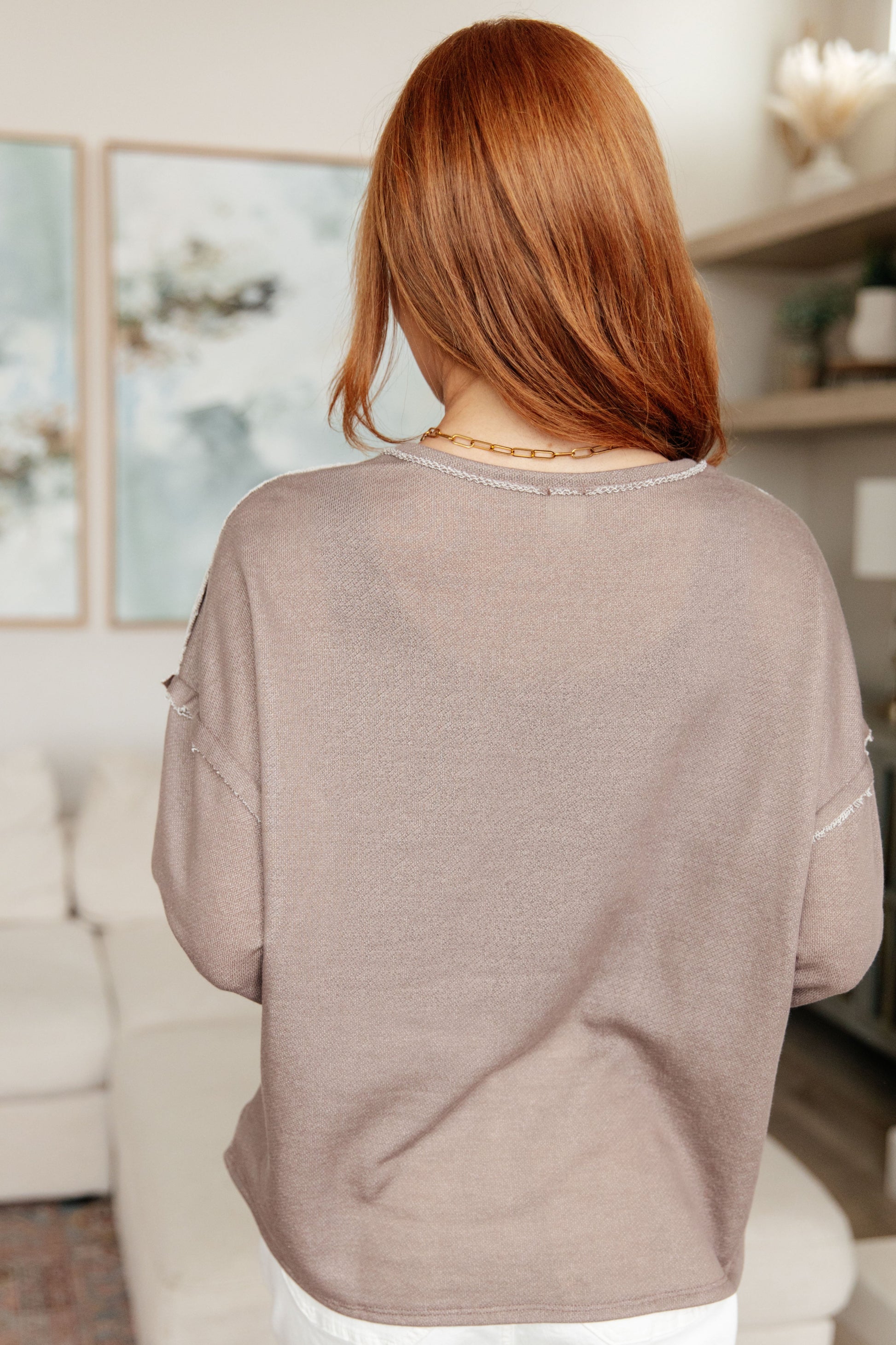 Person wearing a beige sweater in a living room setting