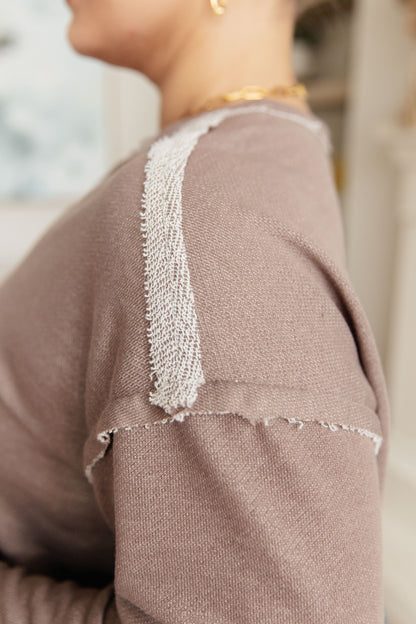 Close-up of a brown garment with white trim, blurred background