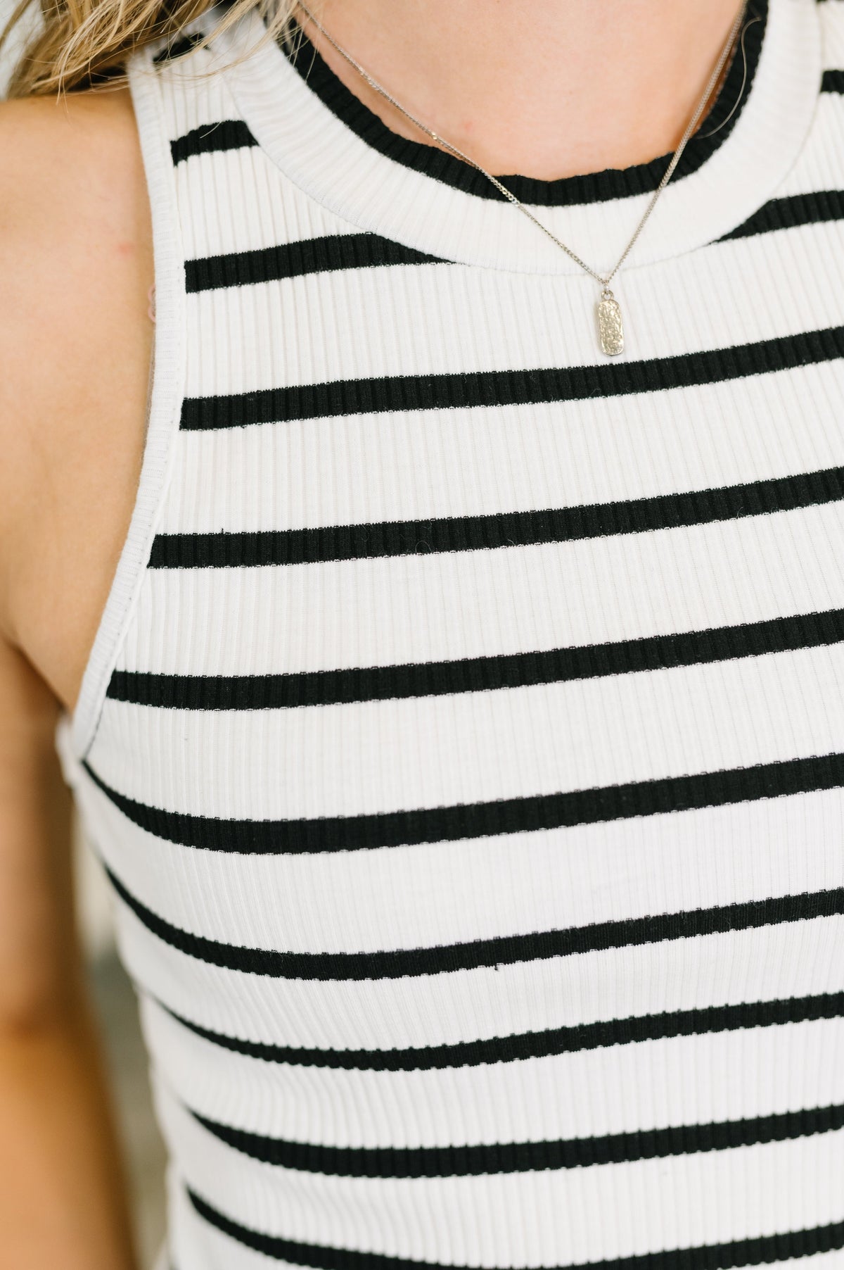 Close-up of a person wearing a black and white striped sleeveless top.