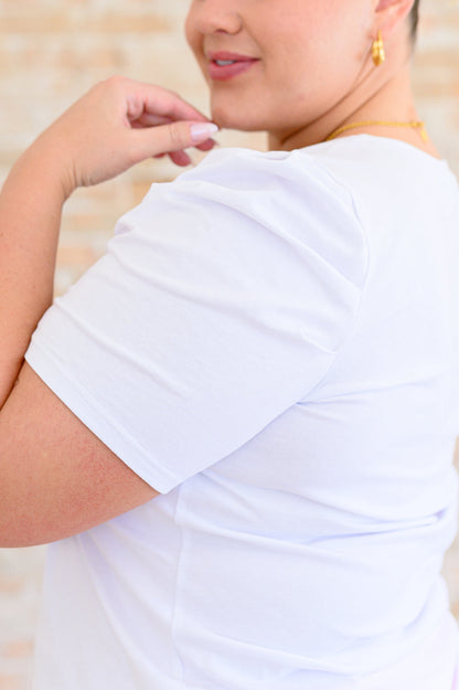A woman wearing a white v-neck tee shirt and a pink paisley mini skirt.