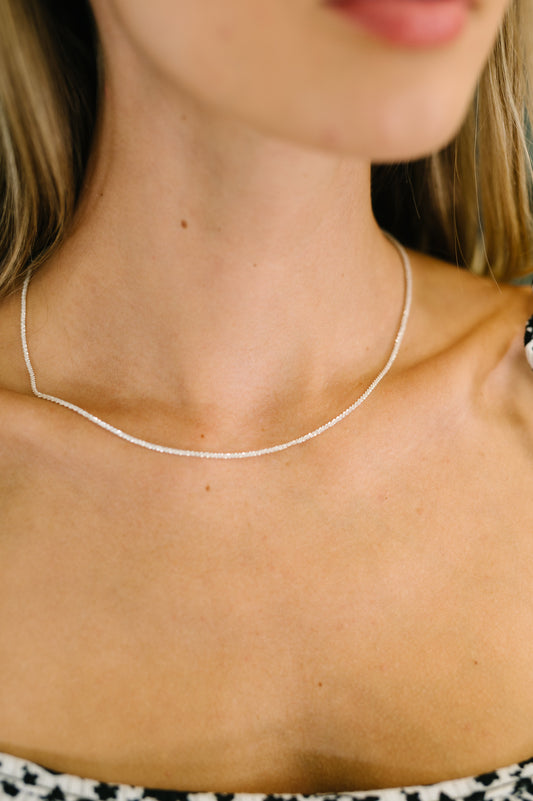 Close-up of a person wearing a delicate silver necklace.