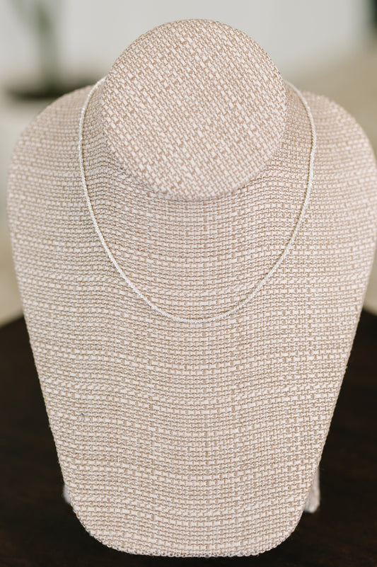Silver beaded necklace on a mannequin bust against a blurred background