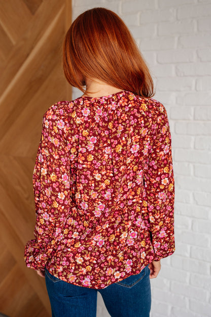 Person wearing a floral blouse with a white brick wall background