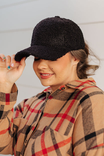 Woman wearing a black cap and plaid shirt against a neutral background