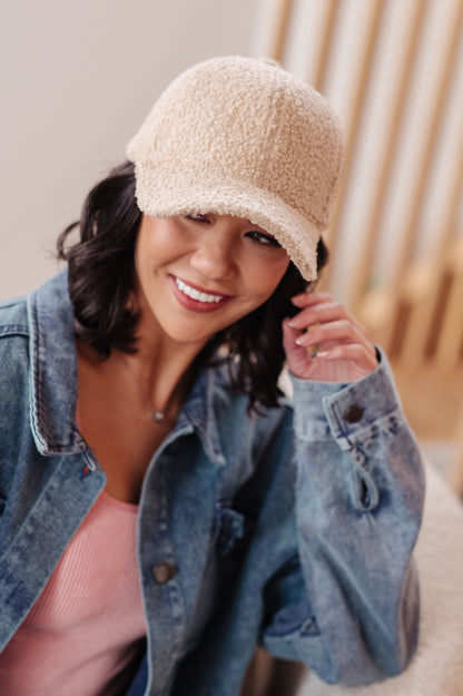 Woman wearing a beige knit cap and denim jacket indoors