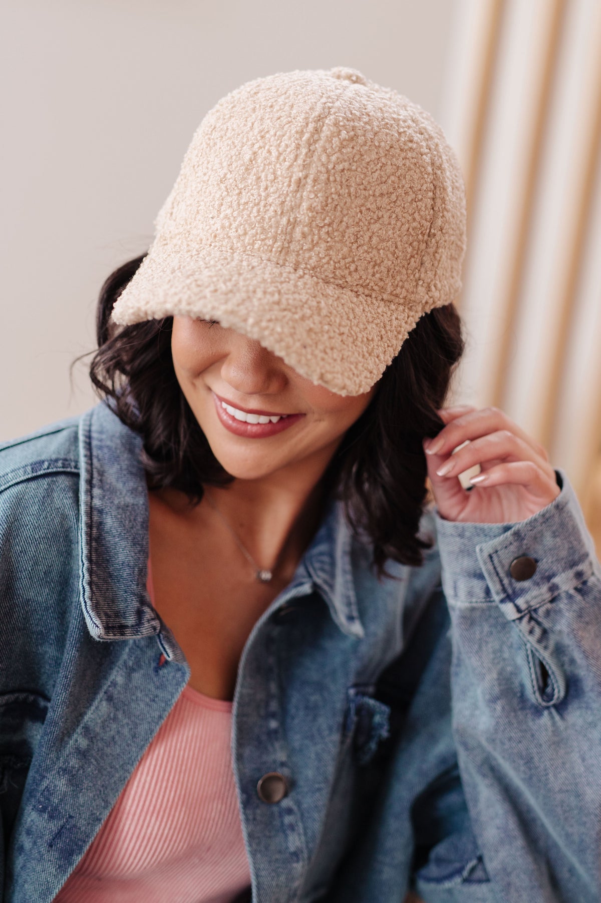 Woman wearing a beige knit hat and denim jacket indoors