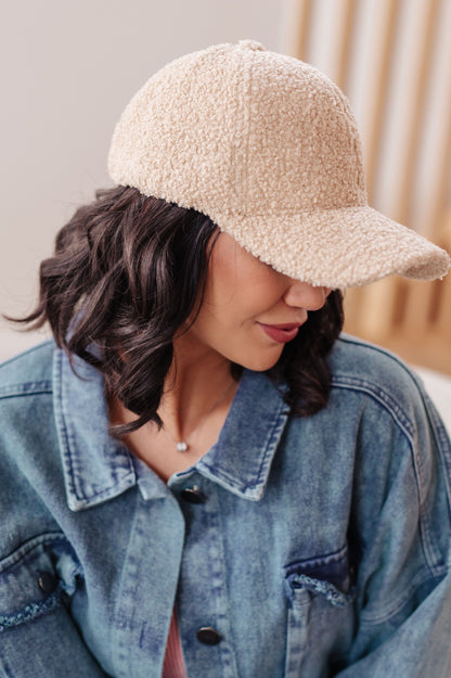 Person wearing a beige sherpa-lined baseball cap and denim jacket.