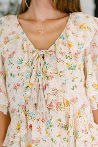 Woman wearing a floral dress with a necklace featuring a heart and arrow pendant.