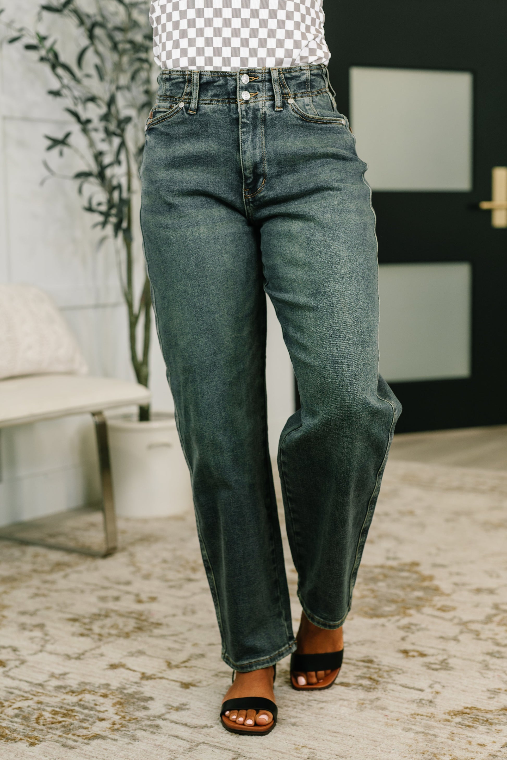 Person wearing blue jeans standing indoors with a blurred background