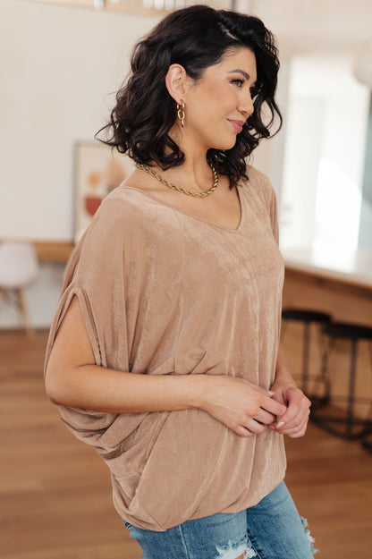 Woman wearing a beige top and blue jeans indoors