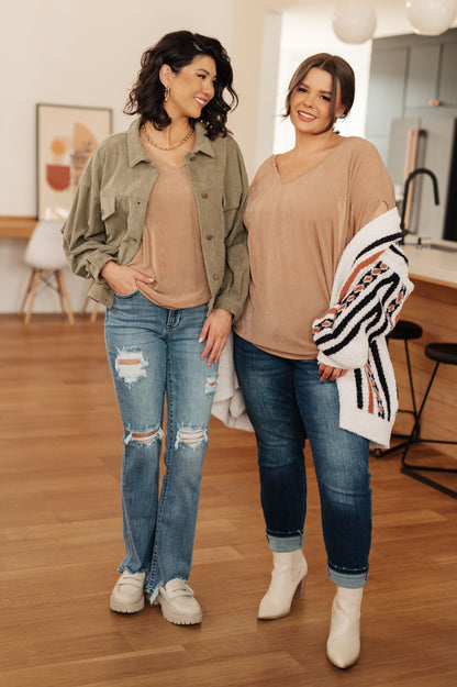 Two women standing indoors wearing casual outfits with jeans and jackets.