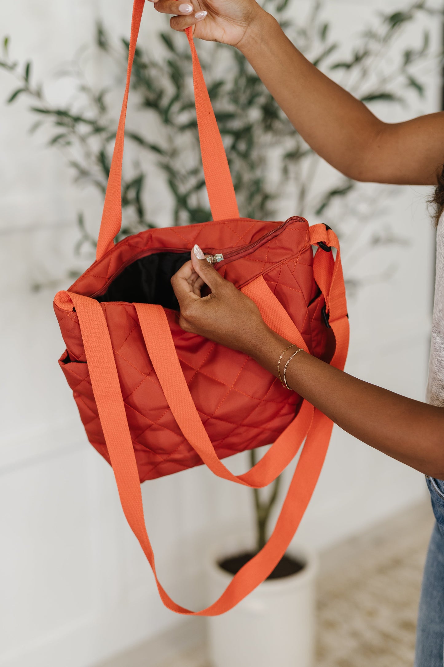 Person holding an orange tote bag with a blurred indoor background