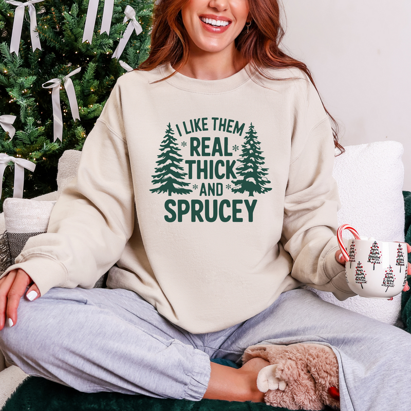 Person wearing a sweater with a Christmas tree design and text, sitting in front of a decorated Christmas tree.