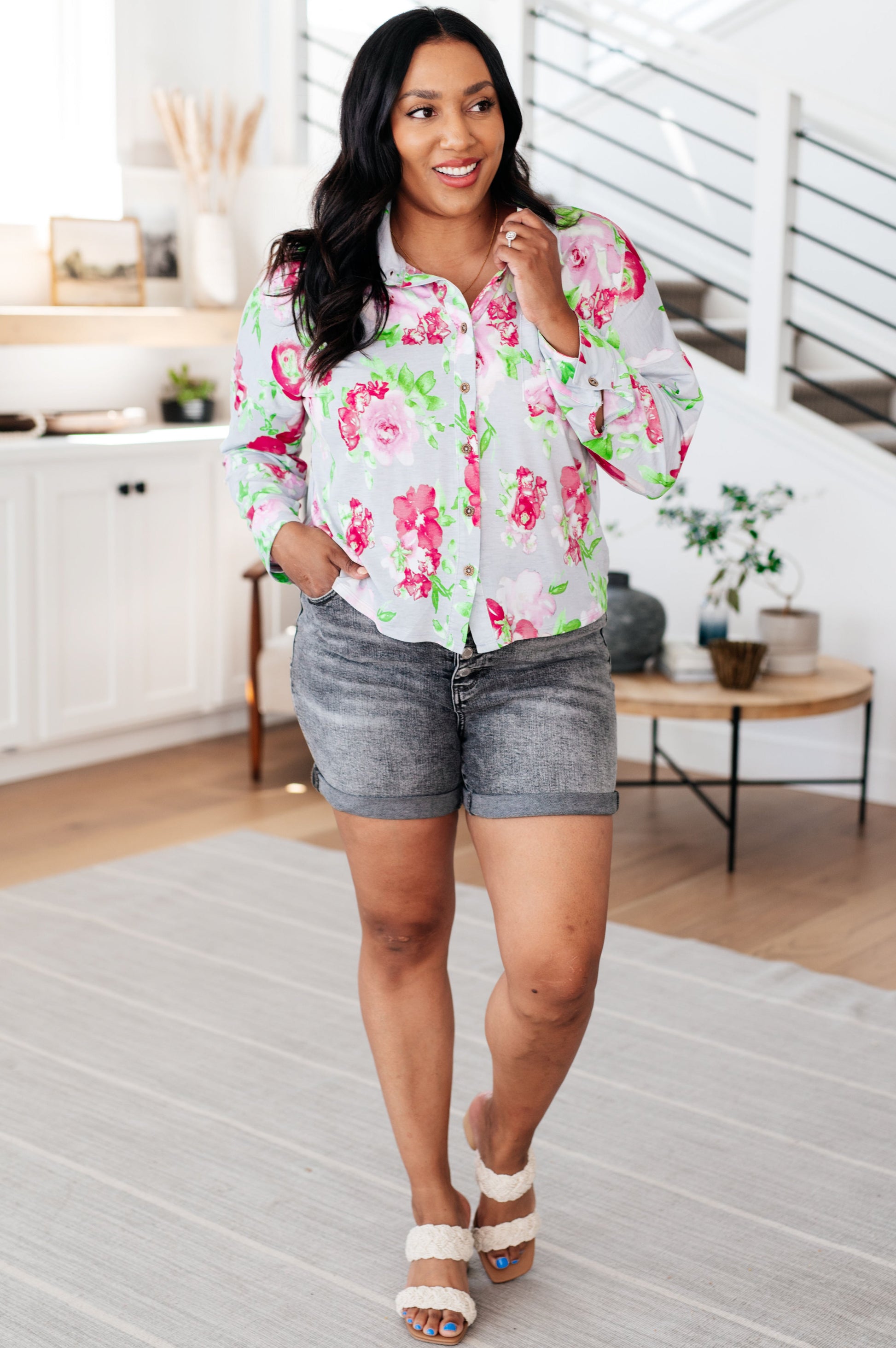 Woman wearing a floral blouse and gray shorts in a kitchen setting
