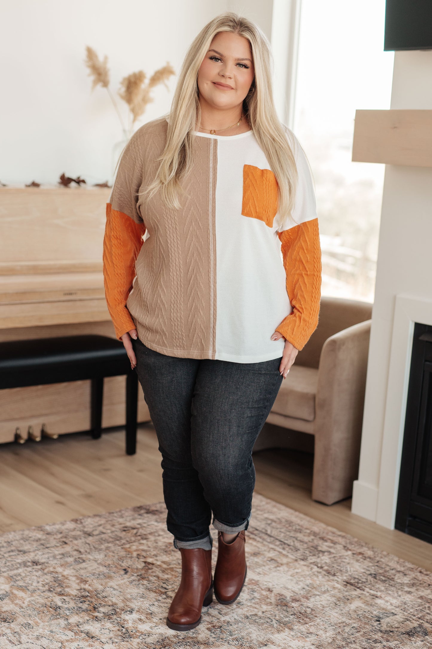 Woman wearing a colorful sweater and jeans in a living room setting