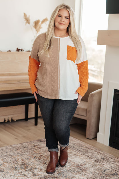 Woman wearing a colorful sweater and jeans in a living room setting