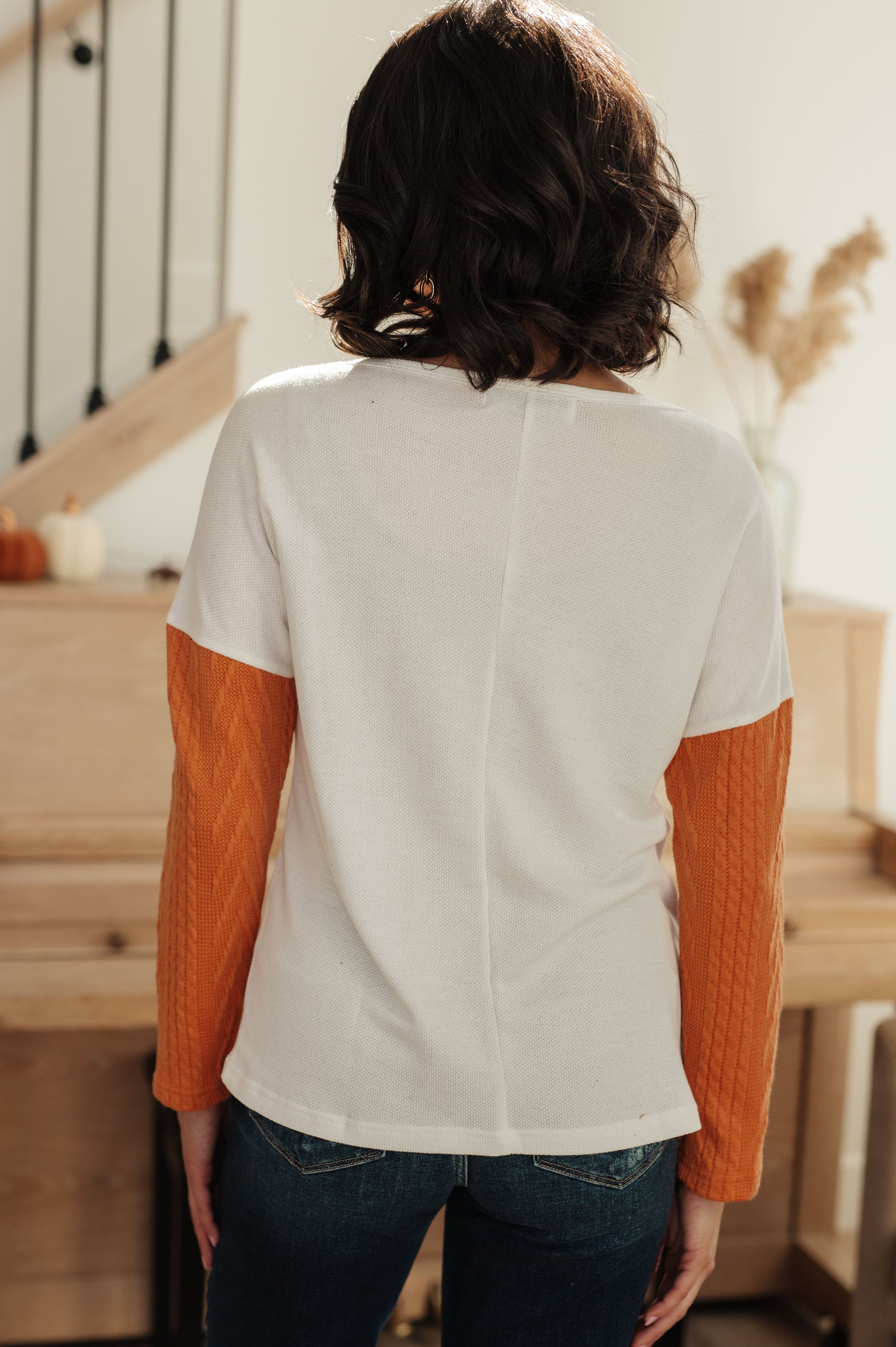 Person wearing a white shirt with orange sleeves in a home setting