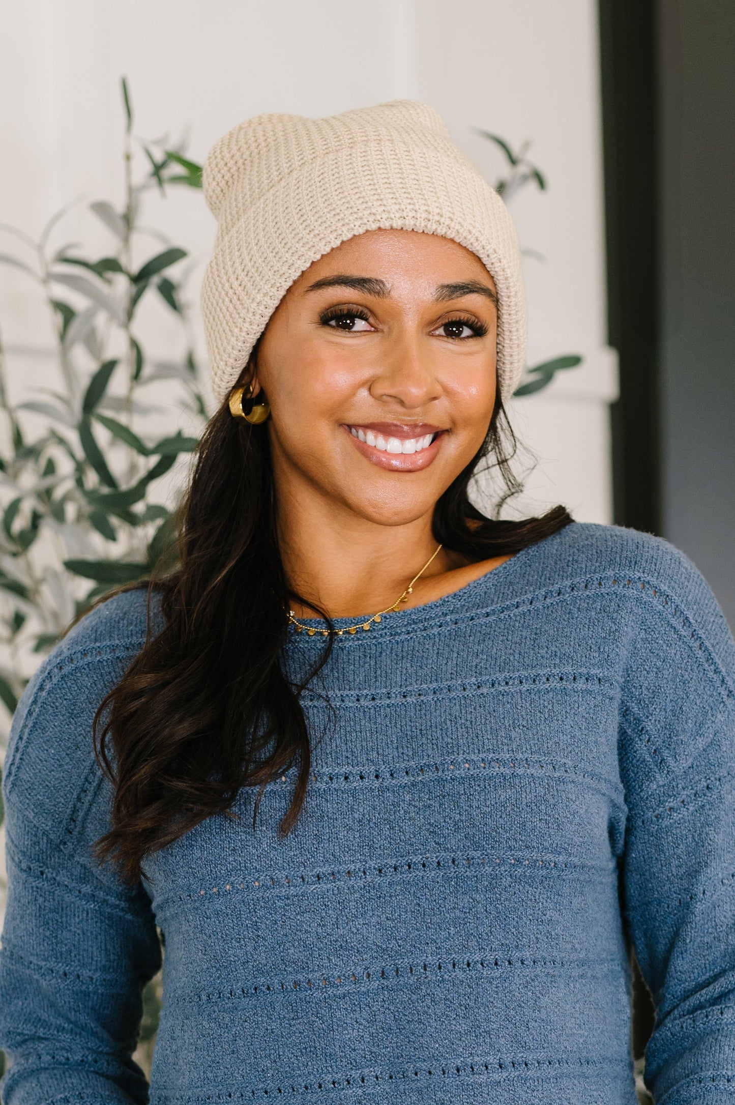 Woman wearing a beige beanie and blue sweater with a blurred background