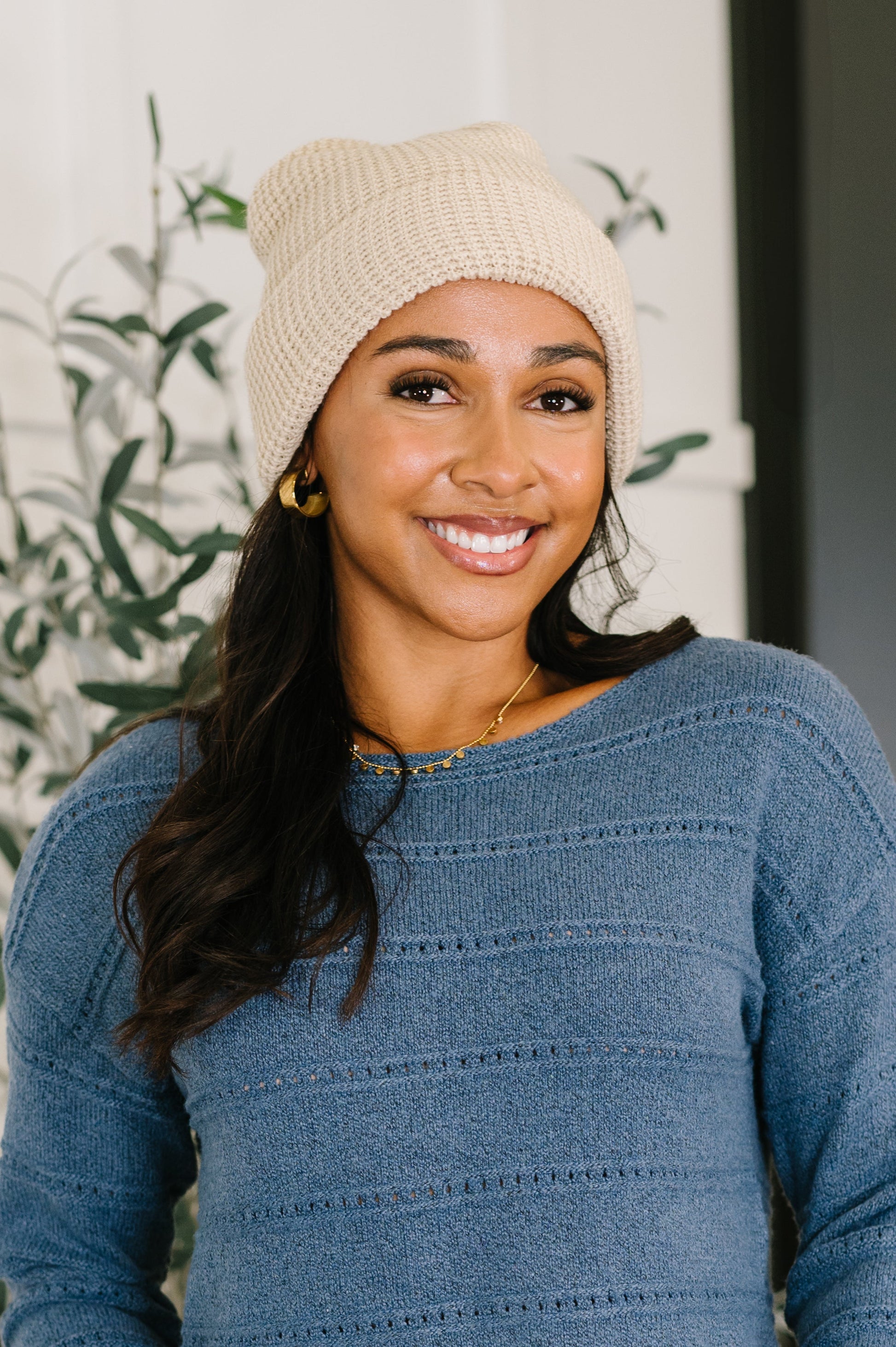 Woman wearing a beige beanie and blue sweater with a blurred background
