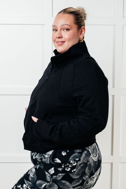 Person wearing a black jacket and patterned pants against a white background