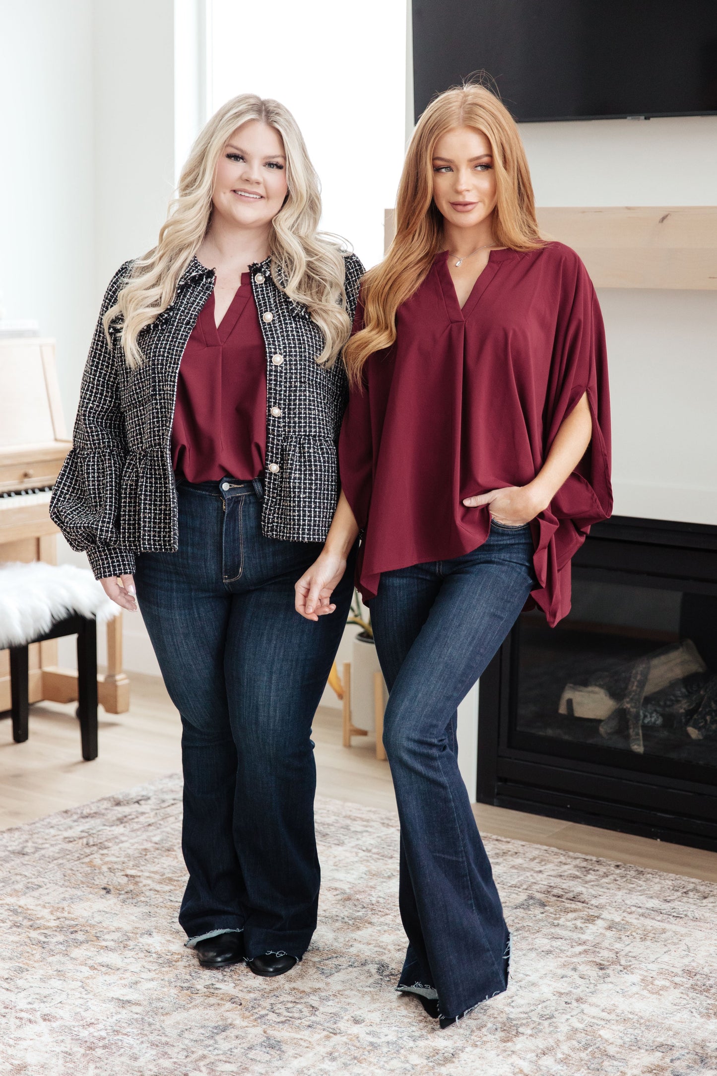 Two women standing in a room wearing matching outfits with maroon tops and blue jeans.
