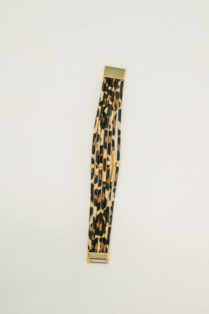 Leopard print belt with gold buckle on a light gray background