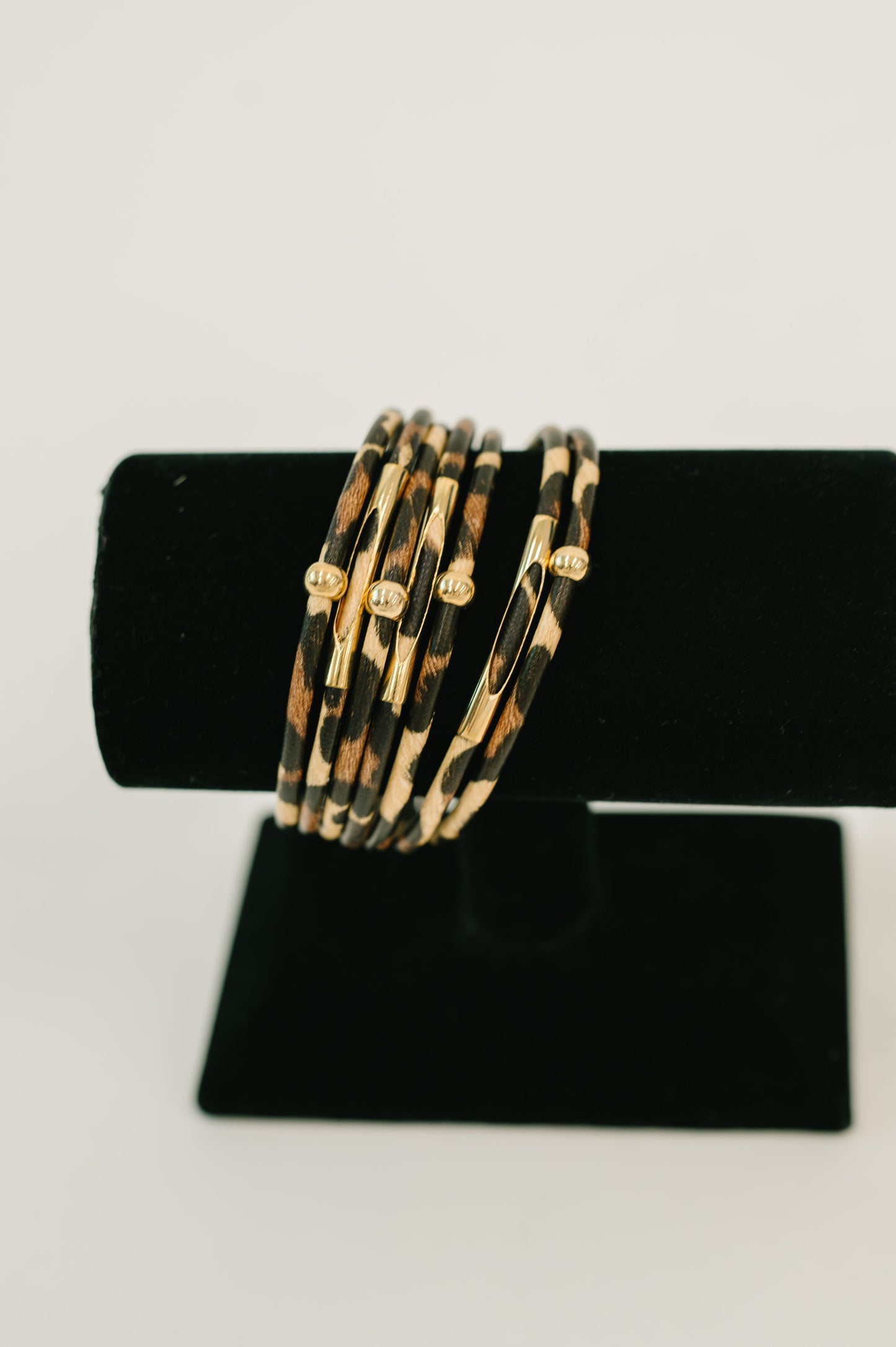 Set of gold and tortoiseshell bangles on a black stand against a white background