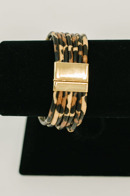 Bracelet with gold clasp on a black stand against a white background