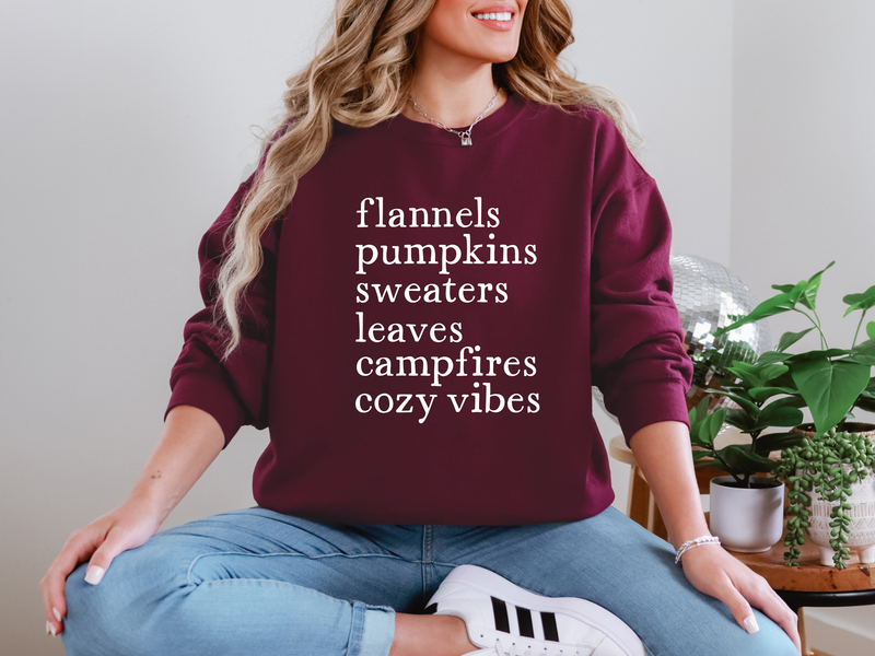 Person wearing a maroon sweatshirt with text, sitting indoors.