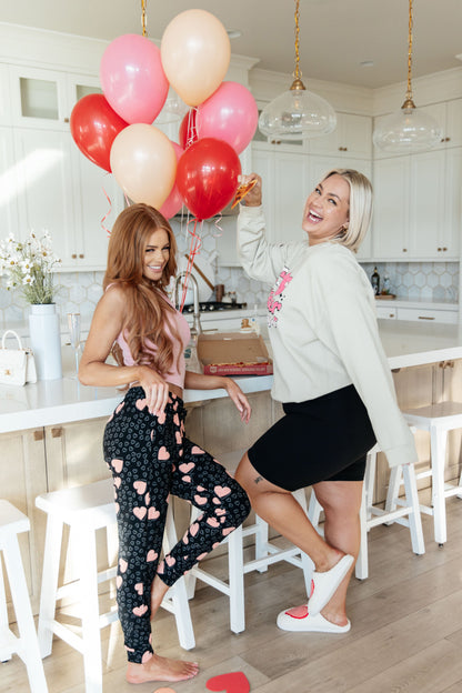 Two women in a kitchen with balloons, one holding a glass of wine.