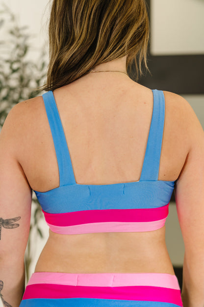 Person wearing a colorful sports bra with blue and pink straps.