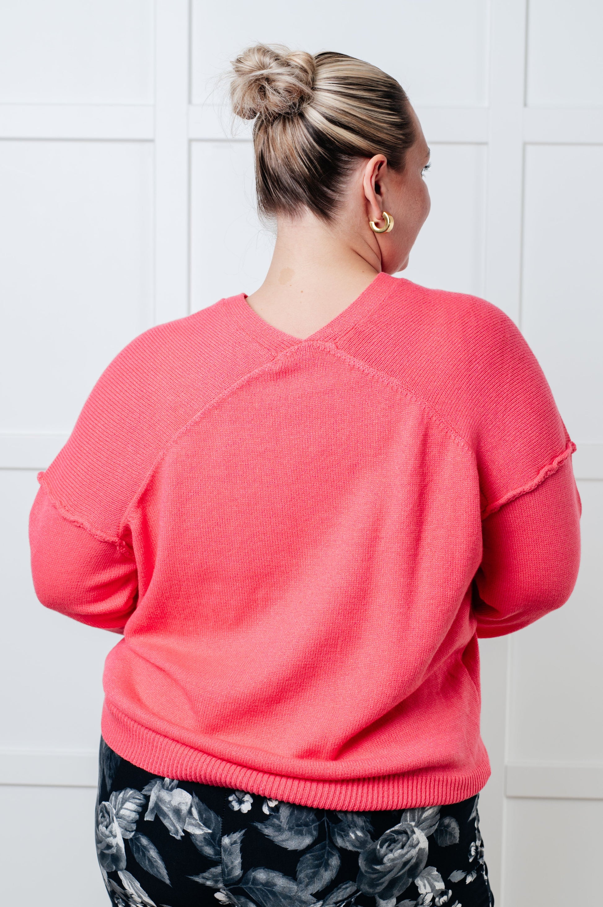 Person wearing a pink sweater with a white tiled wall background