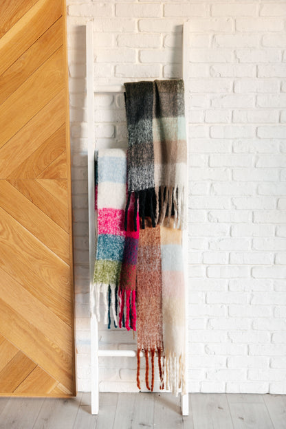 Colorful scarf draped over a white rack against a white brick wall.