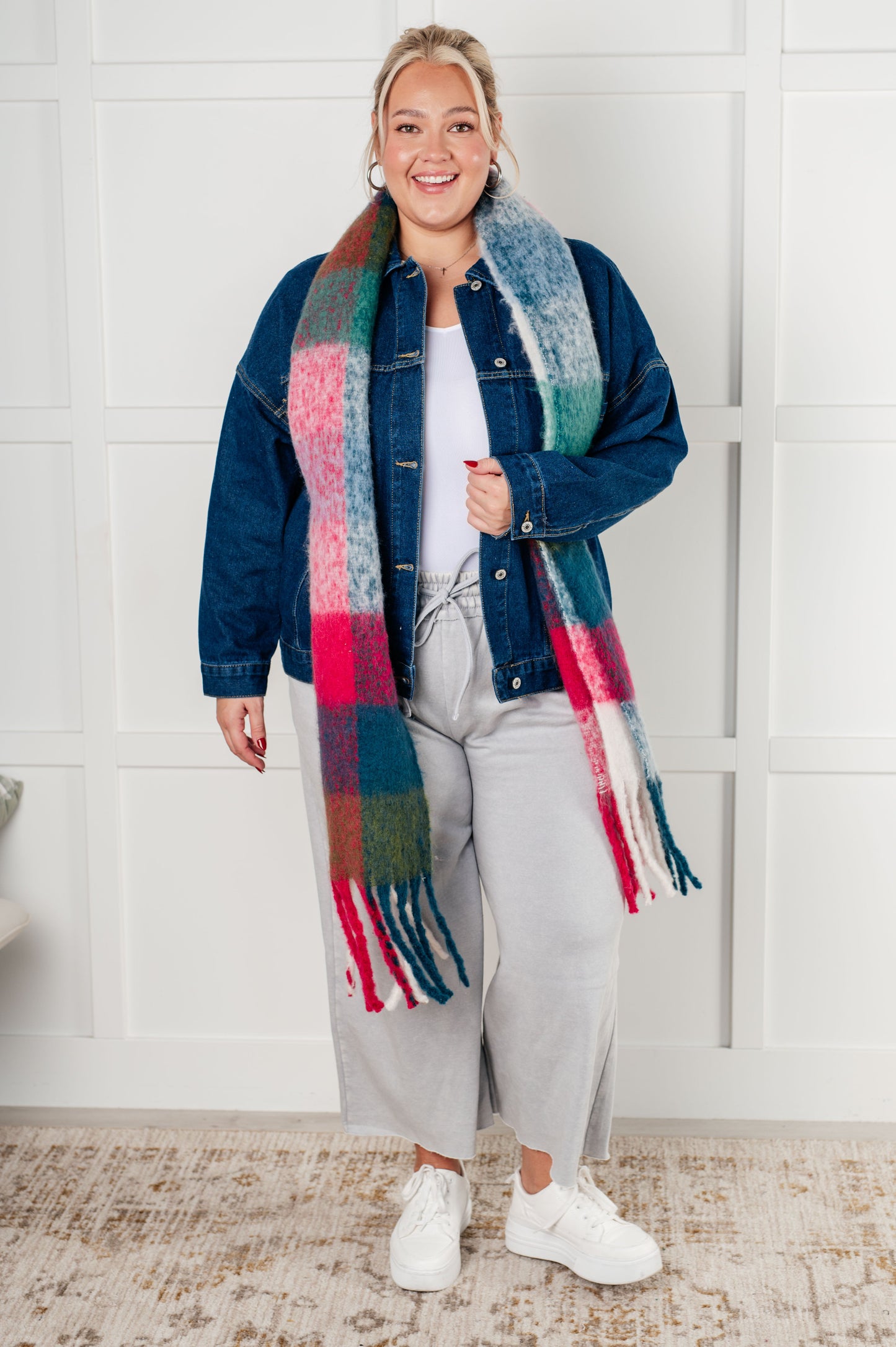 Person wearing a colorful scarf and denim jacket indoors.