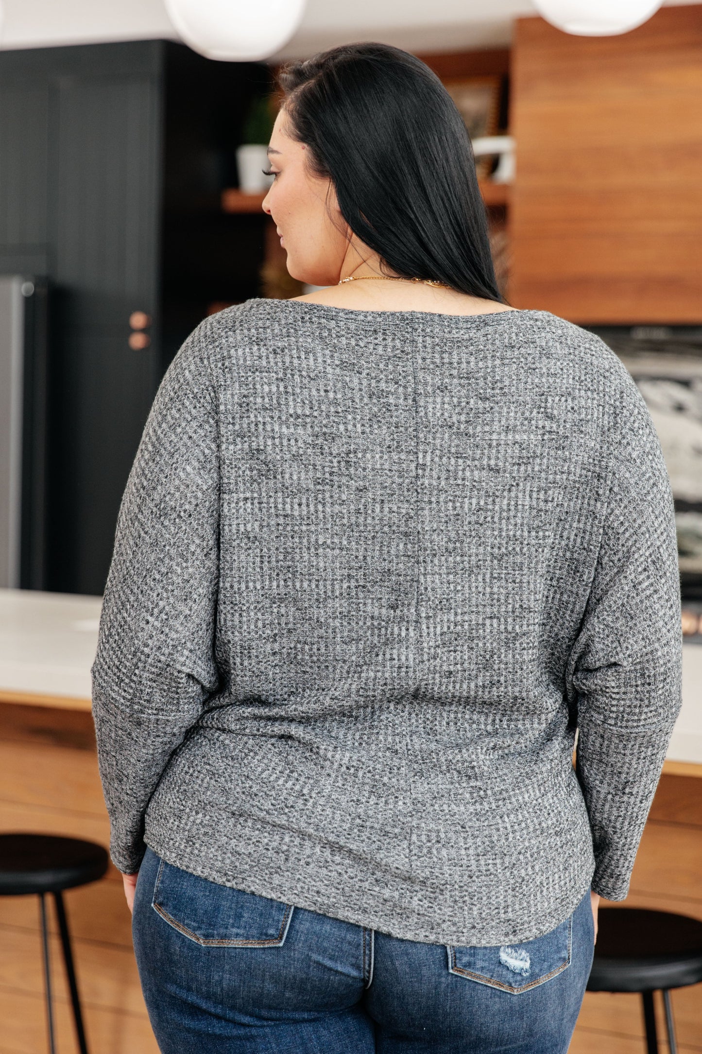 Person wearing a gray sweater in a kitchen setting