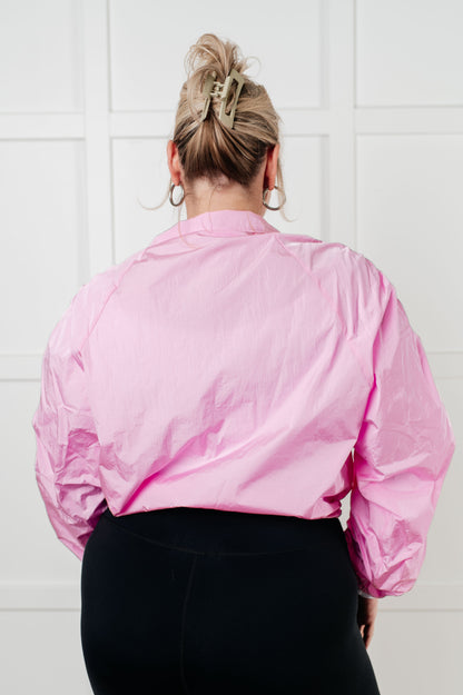 Person wearing a pink jacket with a white wall background