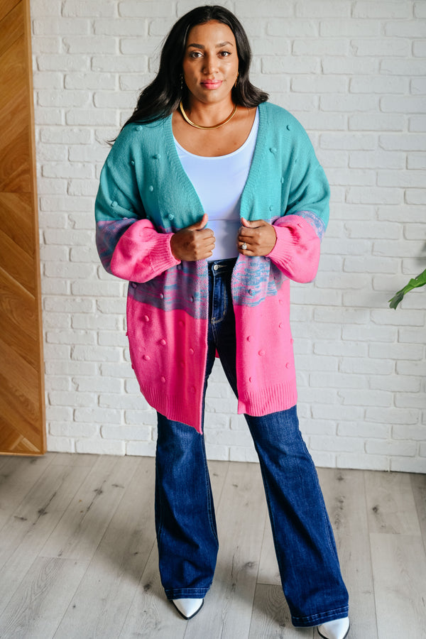 Woman wearing a colorful cardigan with a white brick wall background