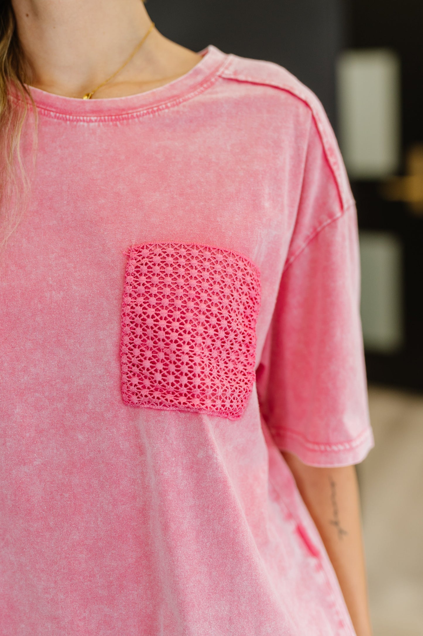 Pink t-shirt with a textured pocket on a blurred background