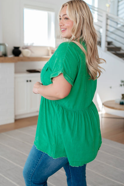 Woman wearing a green top and blue jeans in a kitchen setting