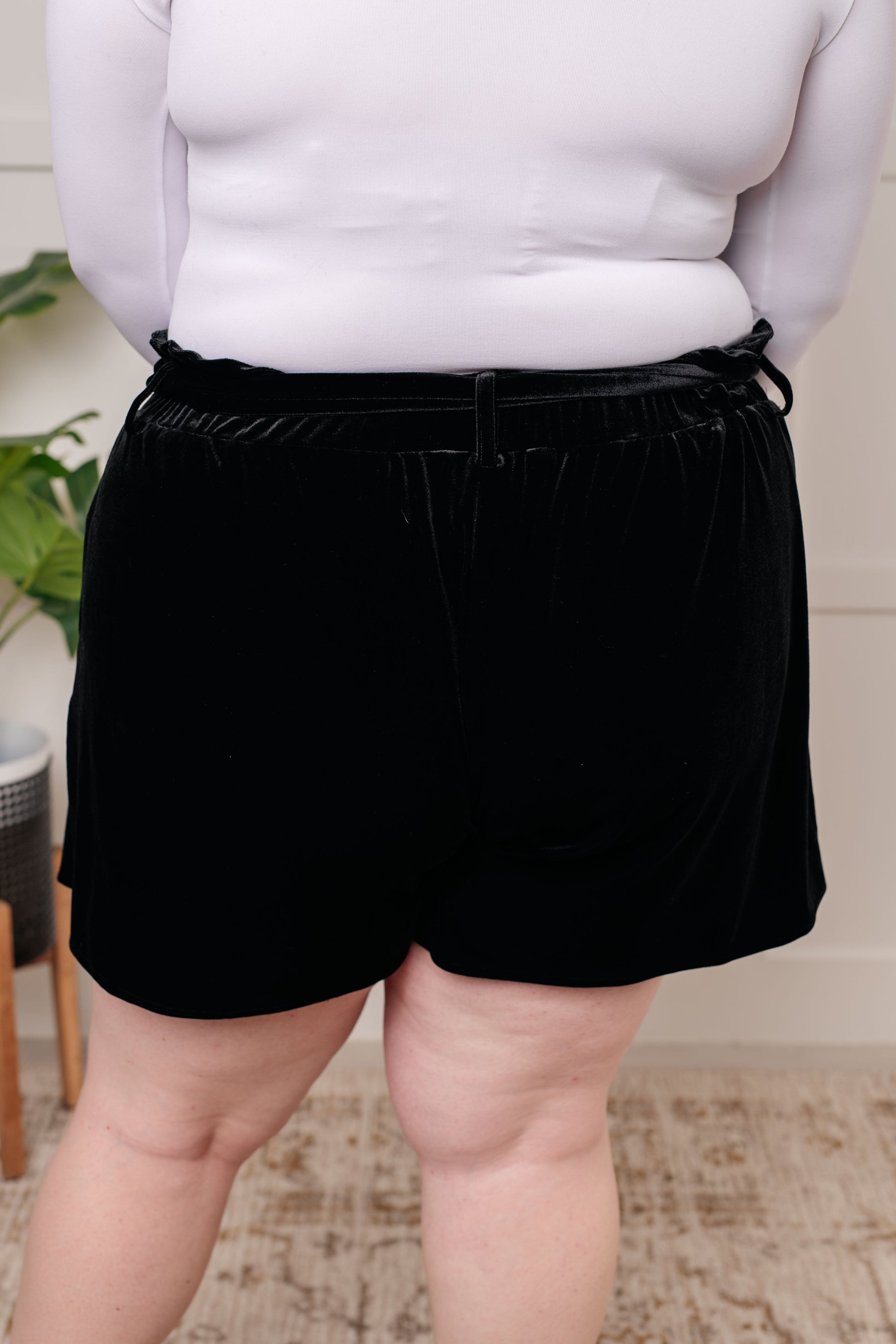 Person wearing black shorts and a white top indoors.