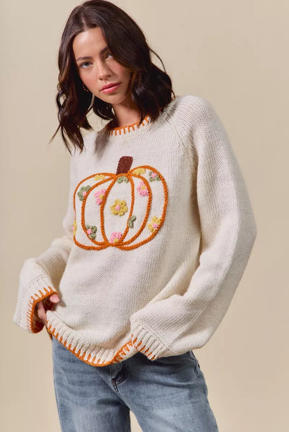 Woman wearing a cream sweater with a pumpkin design on a beige background