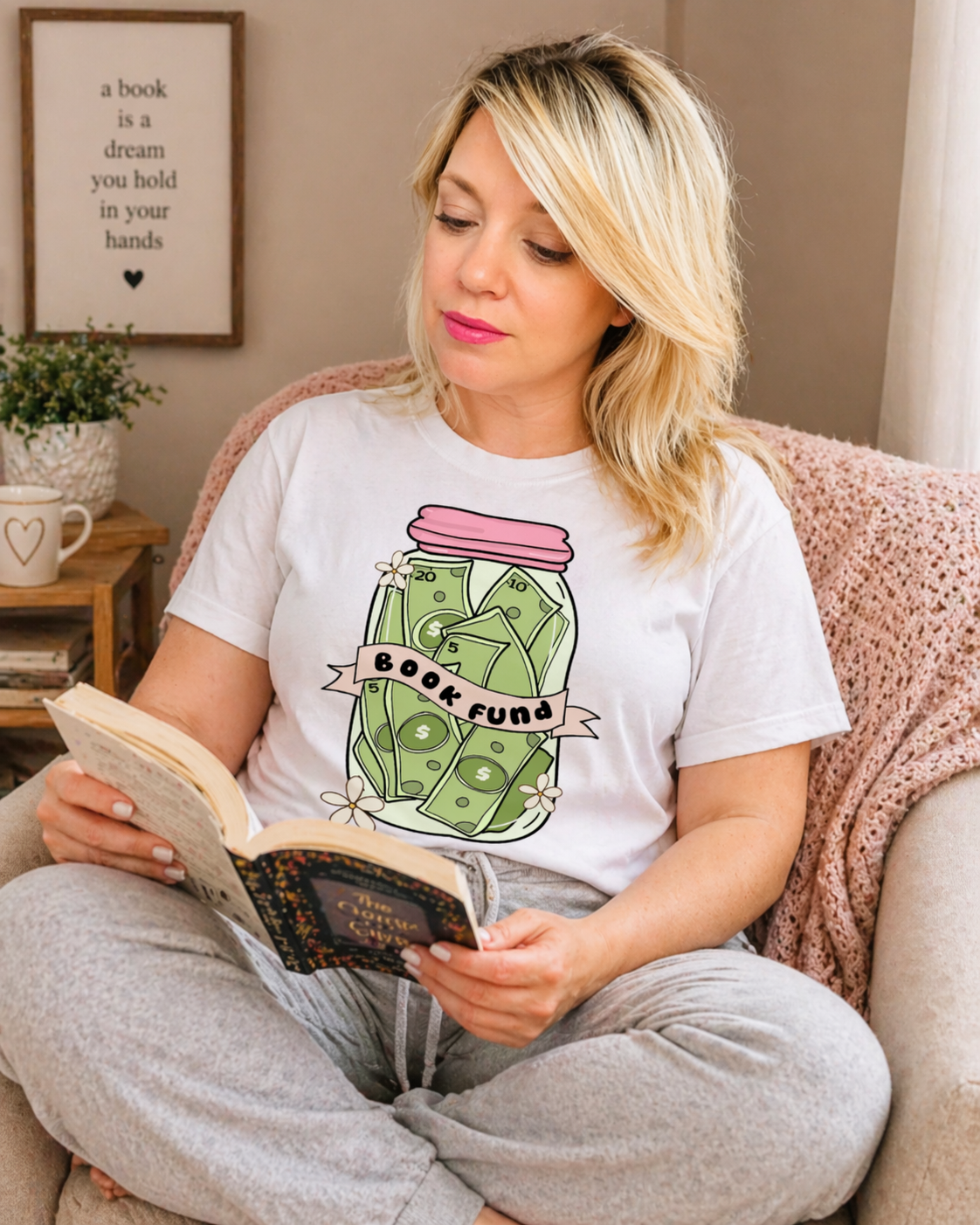Woman reading a book wearing a t-shirt with a 'Book Fund' design.